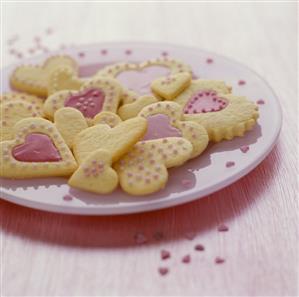 Heart-shaped biscuits with pink icing and sugar pearls