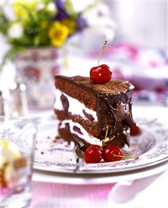 A piece of chocolate cream gateau with cherries