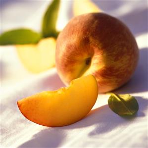 Peach wedge in front of whole peach