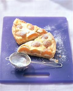 Quark tart with apricots, sieve with icing sugar in front