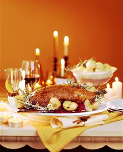 Roast goose with red cabbage and apple on festive table