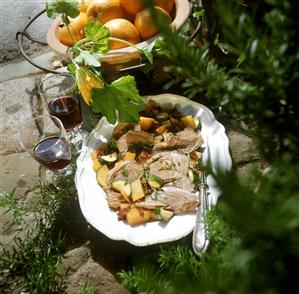 Leg of lamb on vegetables with oranges and dried tomatoes