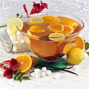 Orange punch in a punch bowl, ingredients beside it