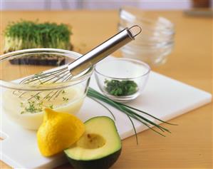 Still life with avocado, lemon, white sauce and herbs