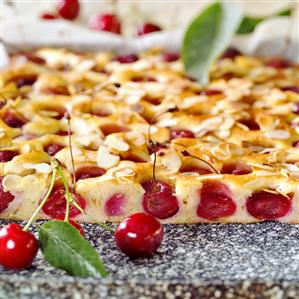 Tray-baked cake with sweet cherries & almonds (a piece cut)