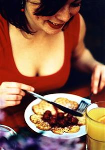 Woman eating waffles with cherry compote