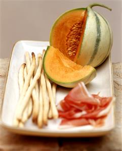 Antipasti still life with ham, honeydew melon and grissini