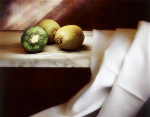 Two whole and one half kiwi fruit on a marble platter