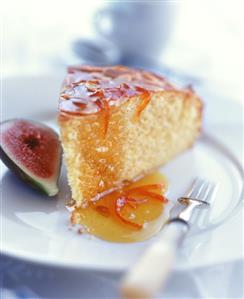 Piece of rich sponge cake with orange sauce; half a fig