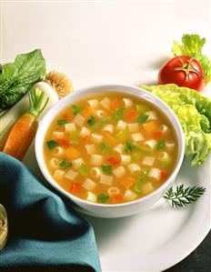 Vegetable broth with noodles, various soup vegetables beside it