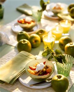 Laid table with fruit salad and green apples