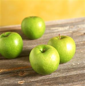 Four Granny Smith apples on wooden background