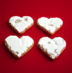 Four heart-shaped almond biscuits with icing sugar