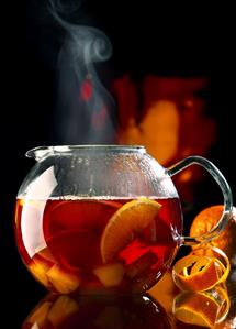 Steaming red wine punch with pieces of fruit in glass teapot