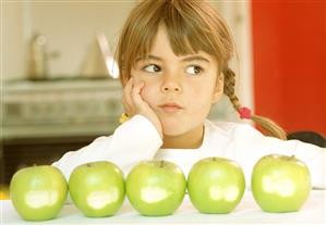 Small girl in front of green apple with bite taken