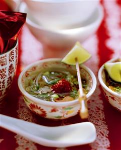 Spicy Asian soup with rice noodles and vegetables in bowl