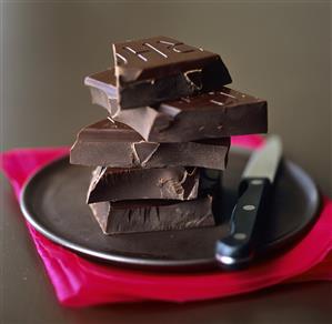 A pile of pieces of Valrhona chocolate on black plate