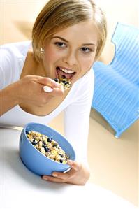 Young woman eating muesli with fresh blueberries (1)