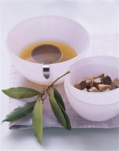 Meat broth with bowl of stewing meat and bay leaves