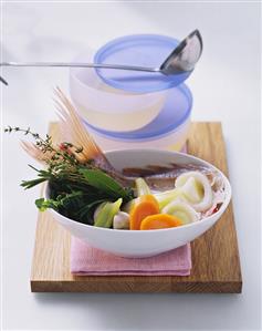 Fish broth & bowl of ingredients (fish, vegetables & herbs)