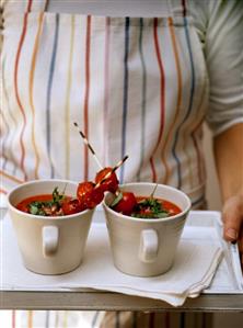 Woman carrying two cups of tomato soup on tray