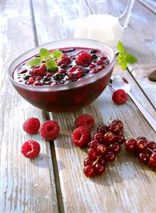 Red berry compote in glass bowl with fresh berries beside it