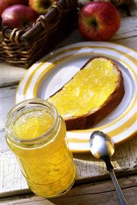 Apple & ginger jelly in jar and on a slice of bread & butter