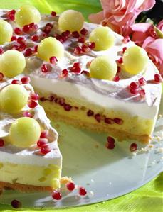 Cream cake, a piece cut, with melon and pomegranate