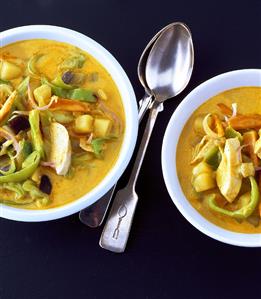 Two plates of curried soup with chicken and vegetables (India)