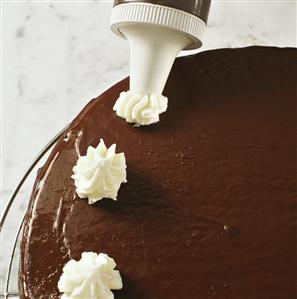 Decorating chocolate cake with cream topping