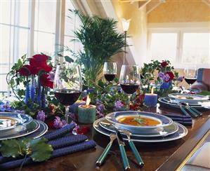 Table laid with soup, wine, roses and ivy