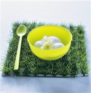 Eggs with flowers in a plastic bowl on artificial grass