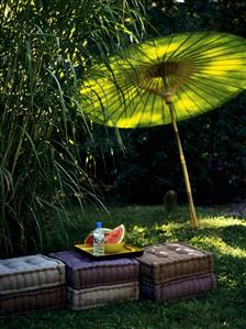 Slices of watermelon on cushions in open air, with green sunshade