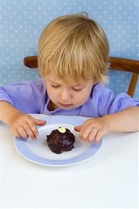 Small boy looking at a small chocolate cake