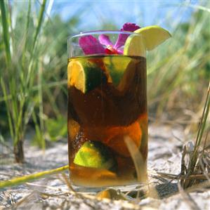 Cuba libre (rum drink with cola) in sand