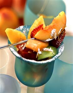 Mixed fruit salad with icing sugar in blue glass (1)