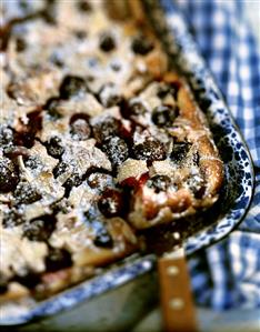 Curd cheese slices with cherries on baking tray with knife