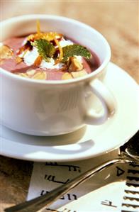 Blueberry soup with flaked almonds, cream & mint in cup