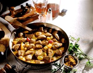 Curried veal fillet with fruit in frying pan