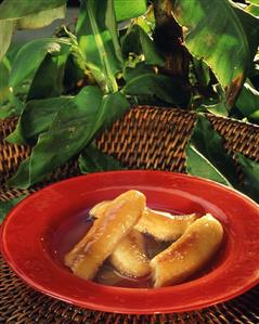 Flambéed bananas in honey sauce on red plate