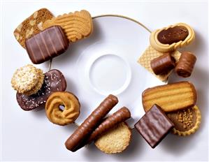 Various biscuits and chocolate rolls, grouped around plate