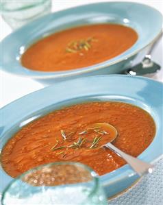 Tomato soup with rosemary in two blue plates