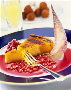 A piece of lemon tart with pomegranate sauce on plate