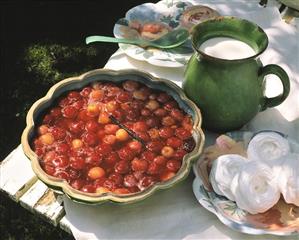 Cherry compote with meringue & milk jug on table in open air