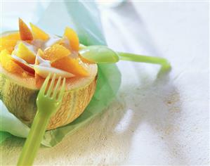 Melon filled with oranges and yoghurt sauce; Plastic cutlery