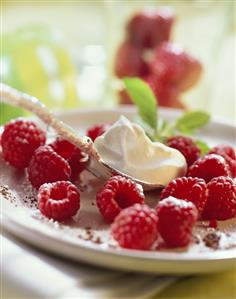 Fresh raspberries on plate with crème fraiche on spoon (1)