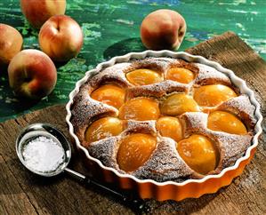 Peach tart with icing sugar in the baking dish