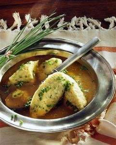 Semolina dumpling soup with chives on a tin plate