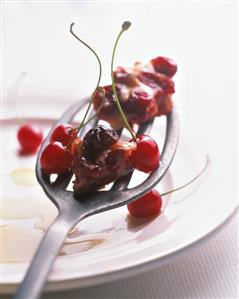 A piece of cherry pudding & cherries on server above plate