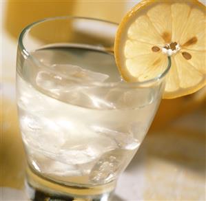 Cold lemon juice drink with lemon slice on the edge of the glass